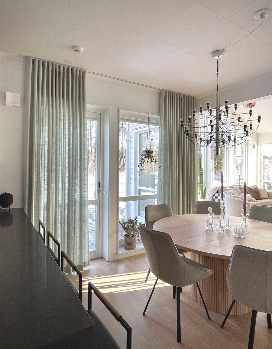 Gardiner i ljusturkos färg i ett ljust, skandinaviskt matrum
