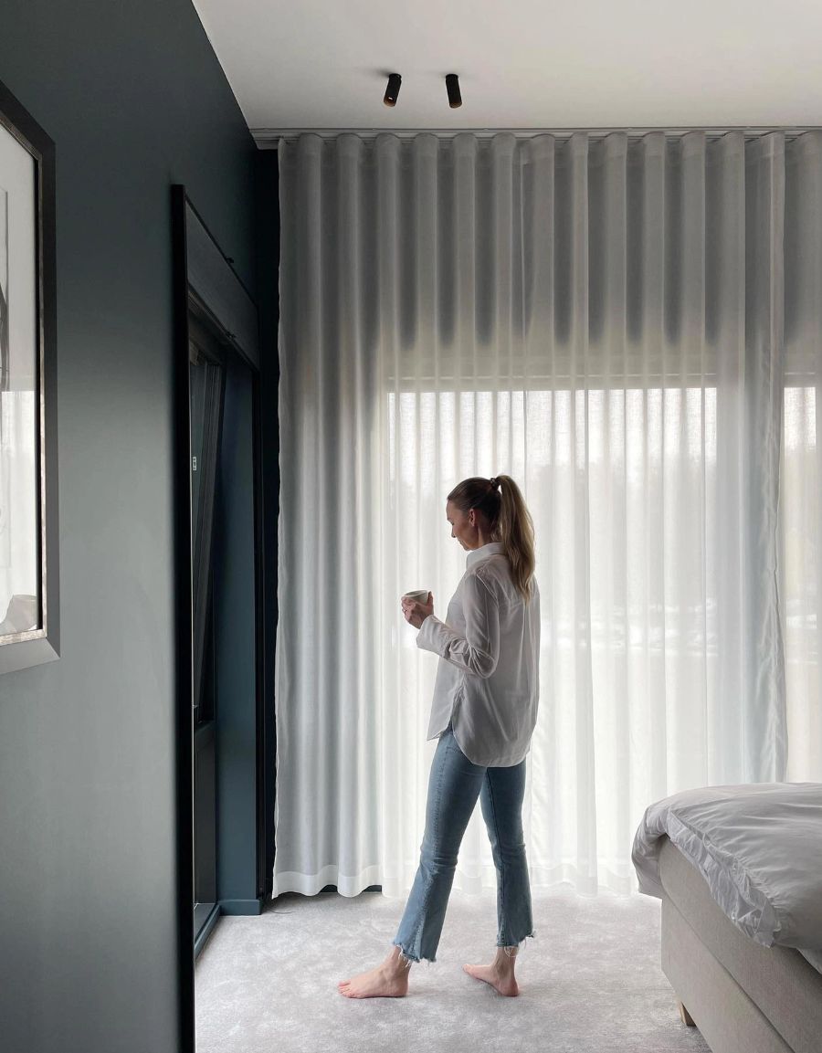 Kvinna framför vita hotellgardiner i sovrum